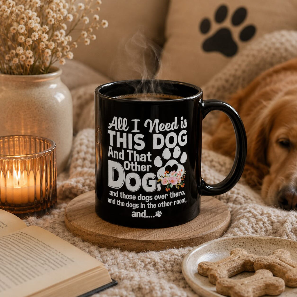 All I Need is This Dog and That Other Dog black mug styled with book, candle, dried flowers, and a golden retriever resting nearby