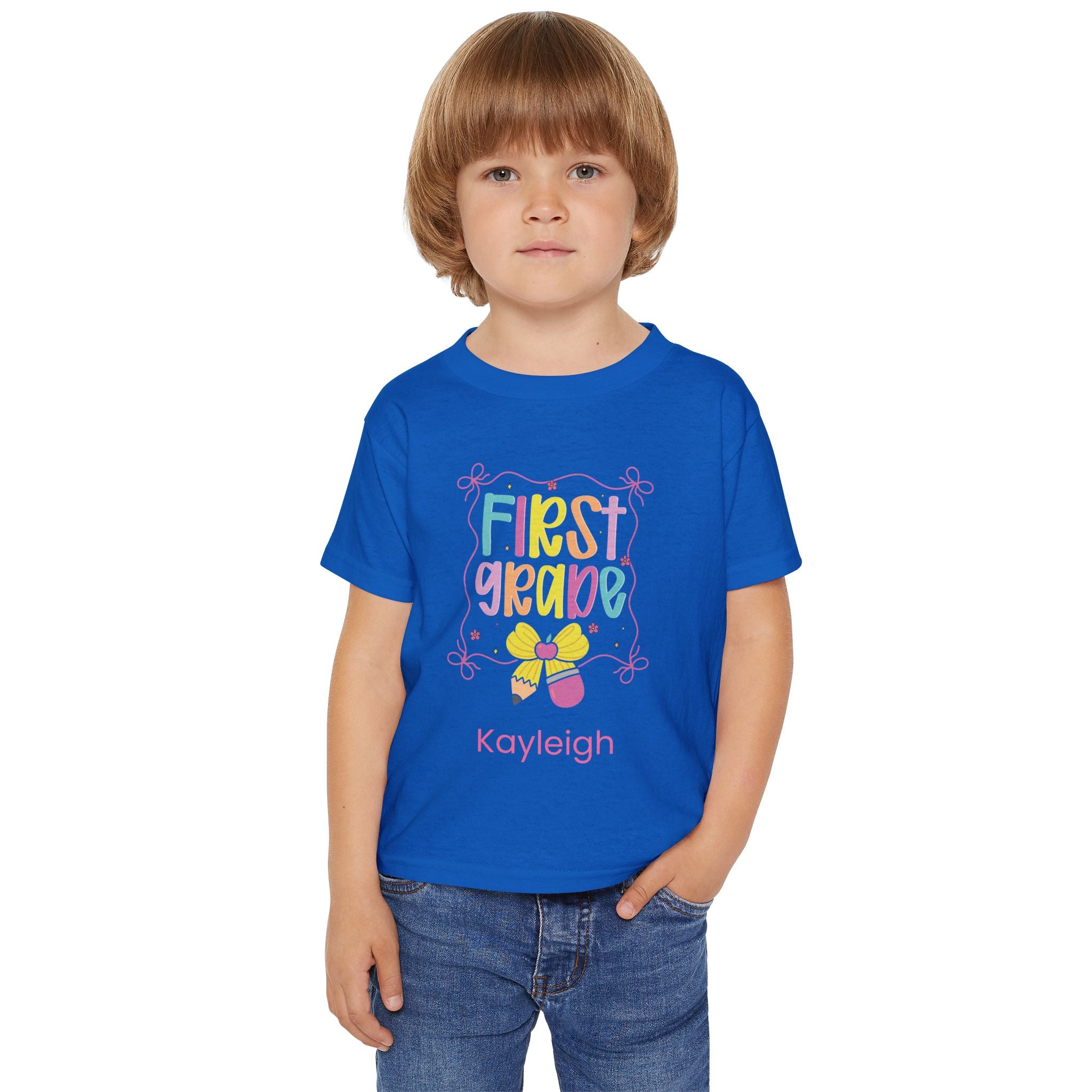 Close-up of First Grade pencil and bow design with custom name on toddler tee