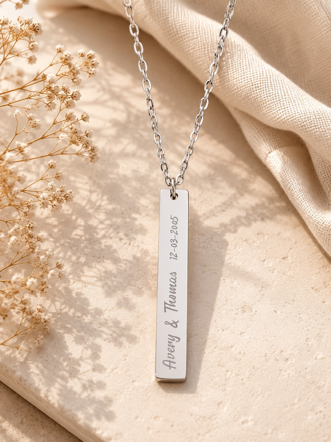 Polished bar necklace close-up of script font engraved names