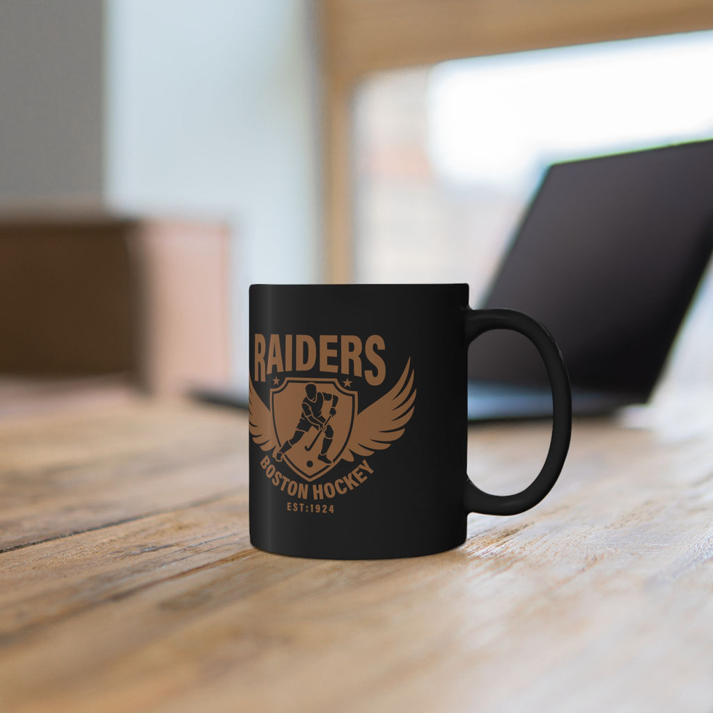 Close-up of Raiders Boston Hockey gold crest on black ceramic mug