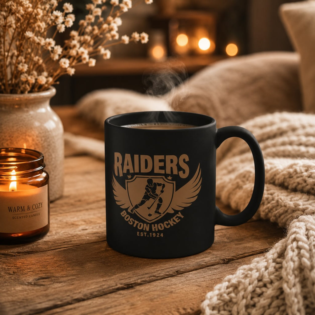 Raiders Boston Hockey black mug styled with warm candlelight, dried flowers, and cozy knit blanket